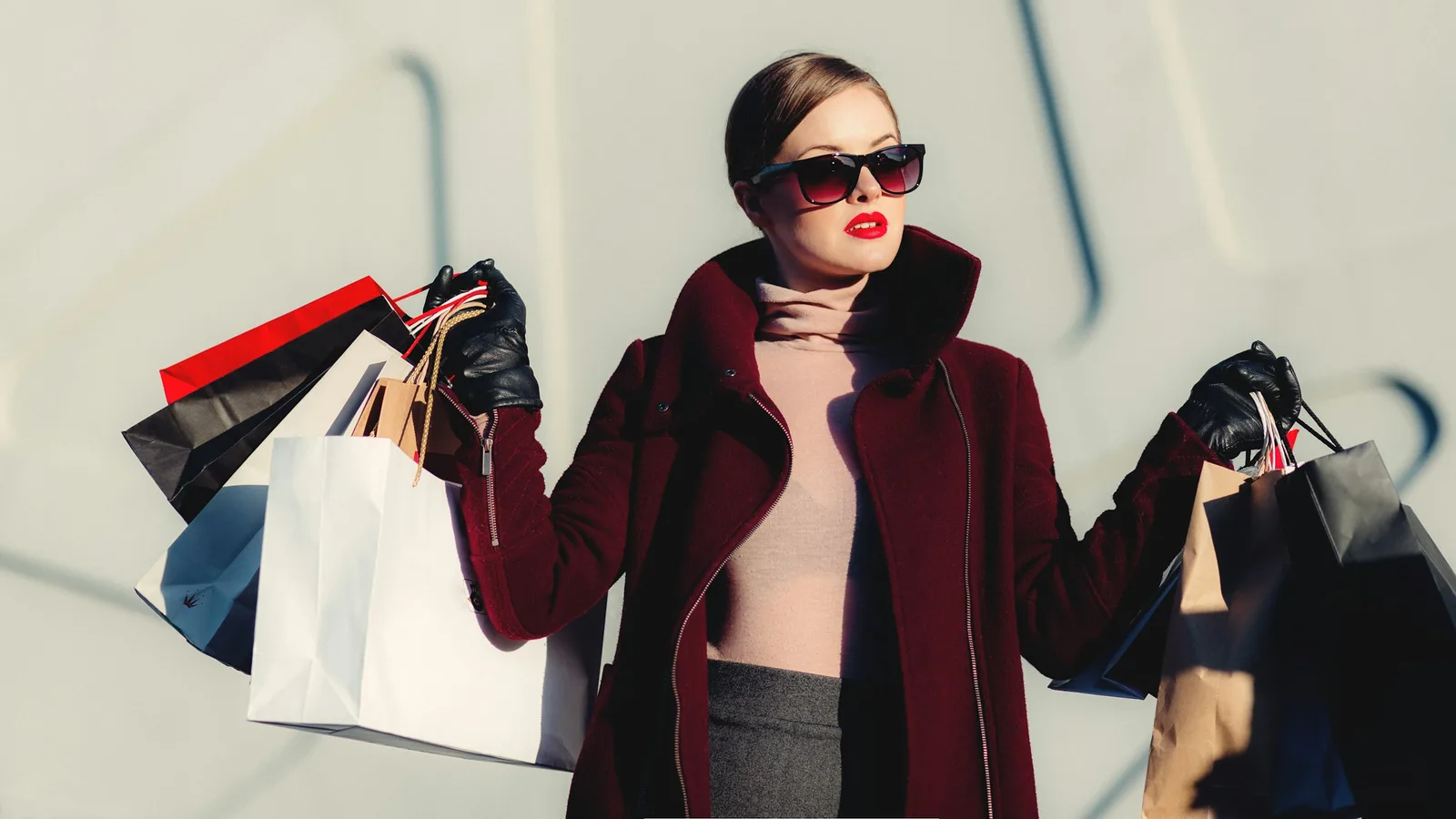Mujer con abrigo vino y bolsas de compras